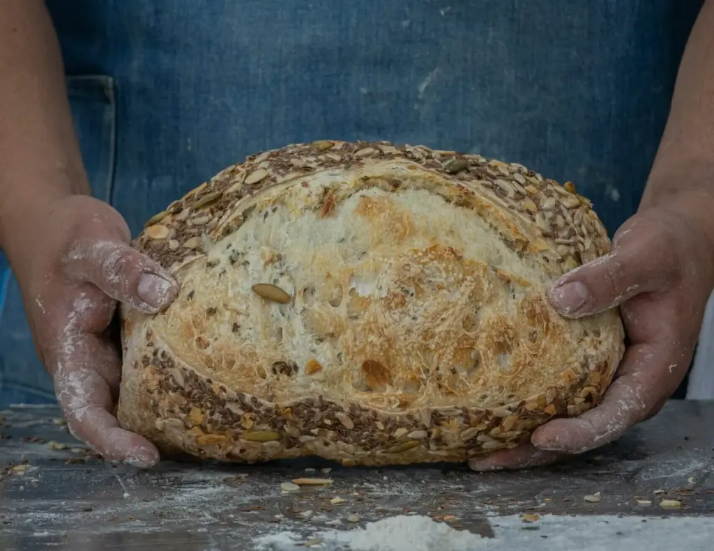 Bäcker hält einen frisch gebackenen Brotlaib in den Händen