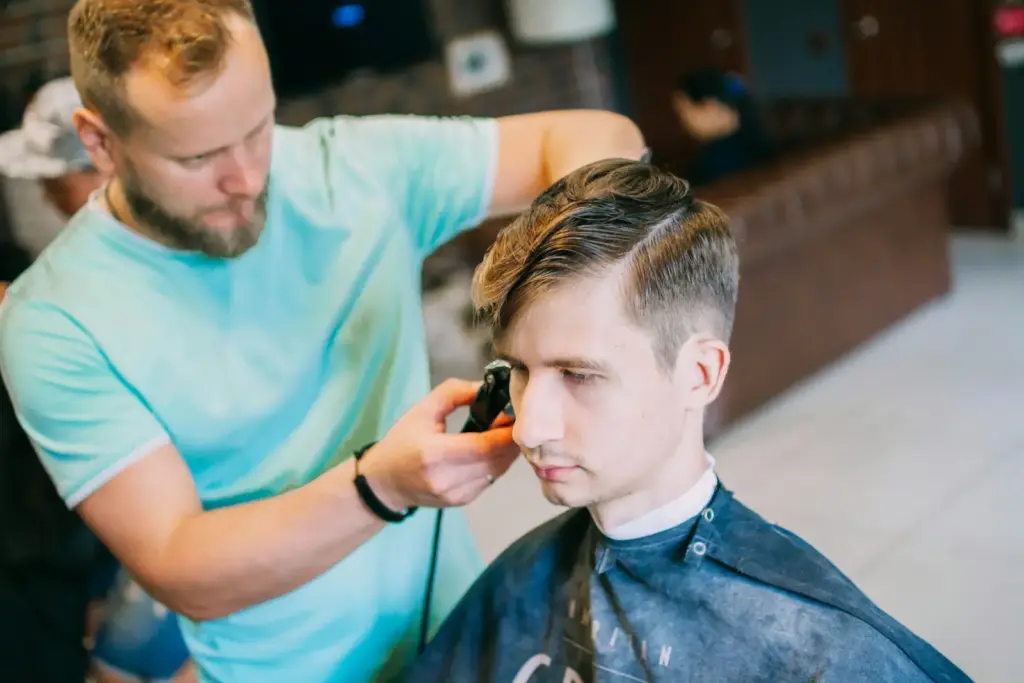 Friseur schneidet einem Kunden die Haare im Salon